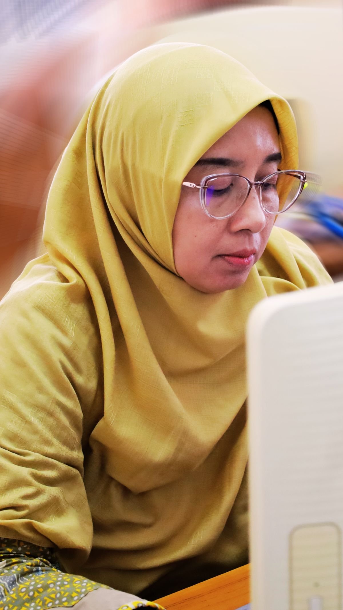 Peserta perempuan berkacamata fokus mengikuti praktik menggunakan komputer.