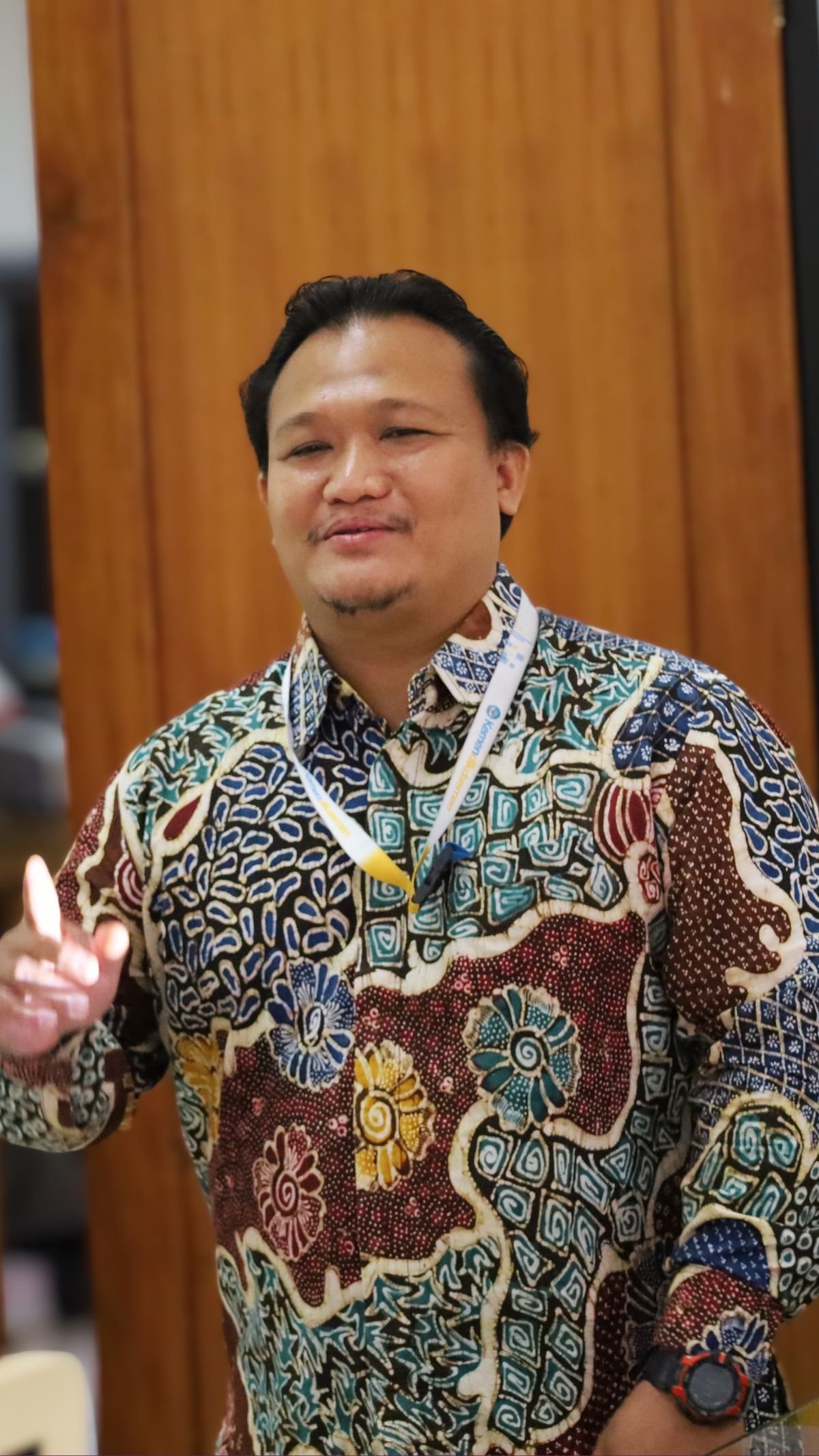 Fasilitator laki-laki berbaju batik menjelaskan materi dalam sesi pelatihan.
